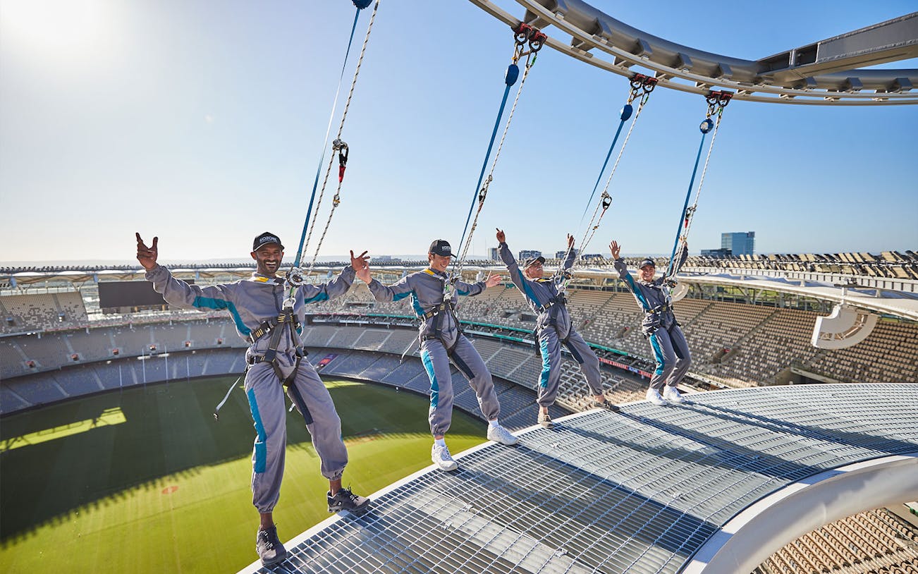 Visitors harnessed on Optus Stadium roof during Vertigo experience in Perth, Australia.