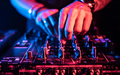 DJ adjusting controls on a music table at a nightclub.