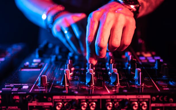 DJ adjusting controls on a music table at a nightclub.