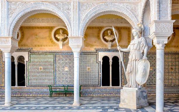 Casa Pilatos Seville, colorful tiled walls with arches and statue.