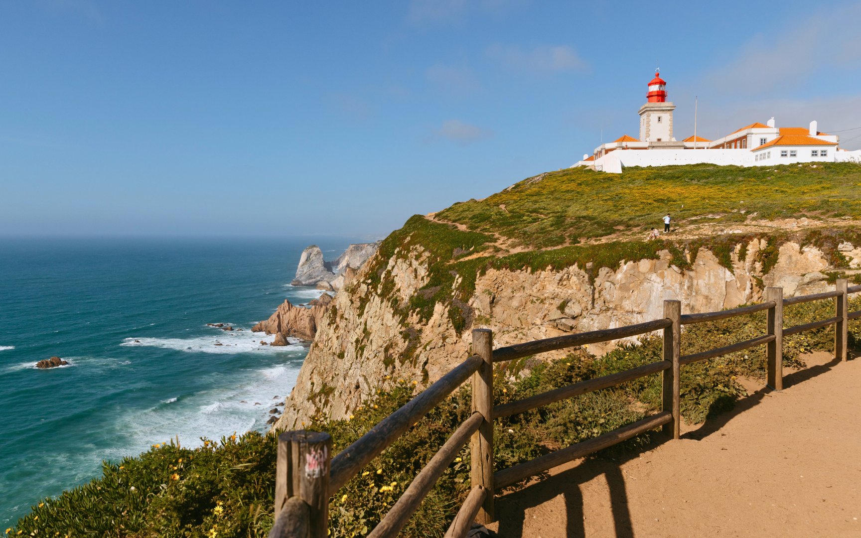 Cabo da Roca lighthouse on cliff overlooking the Atlantic Ocean during evening.