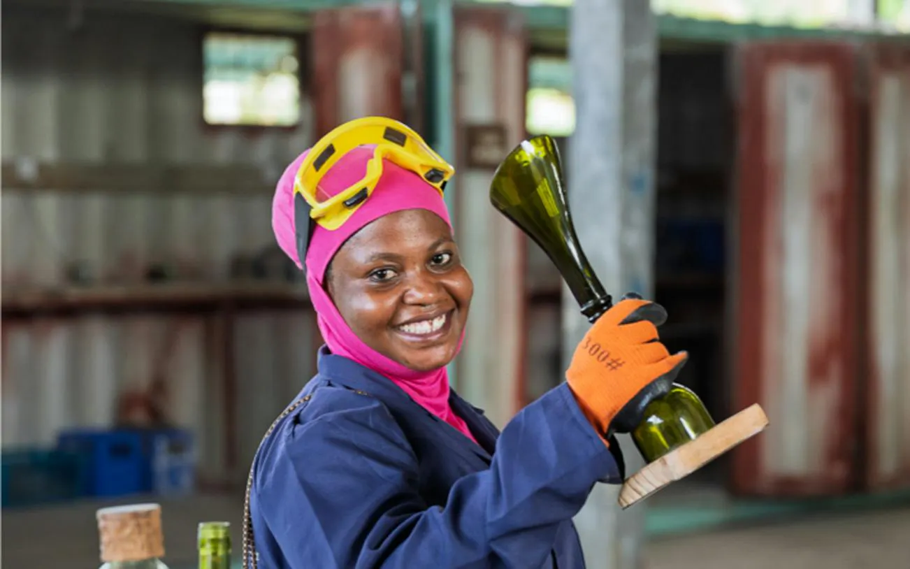 Woman holding upcycled glass bottle in Zanzibar workshop.