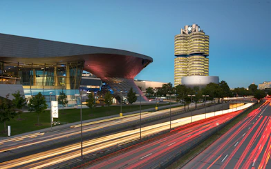 BMW Welt and Headquarters in Munich at dusk with light trails from passing cars.