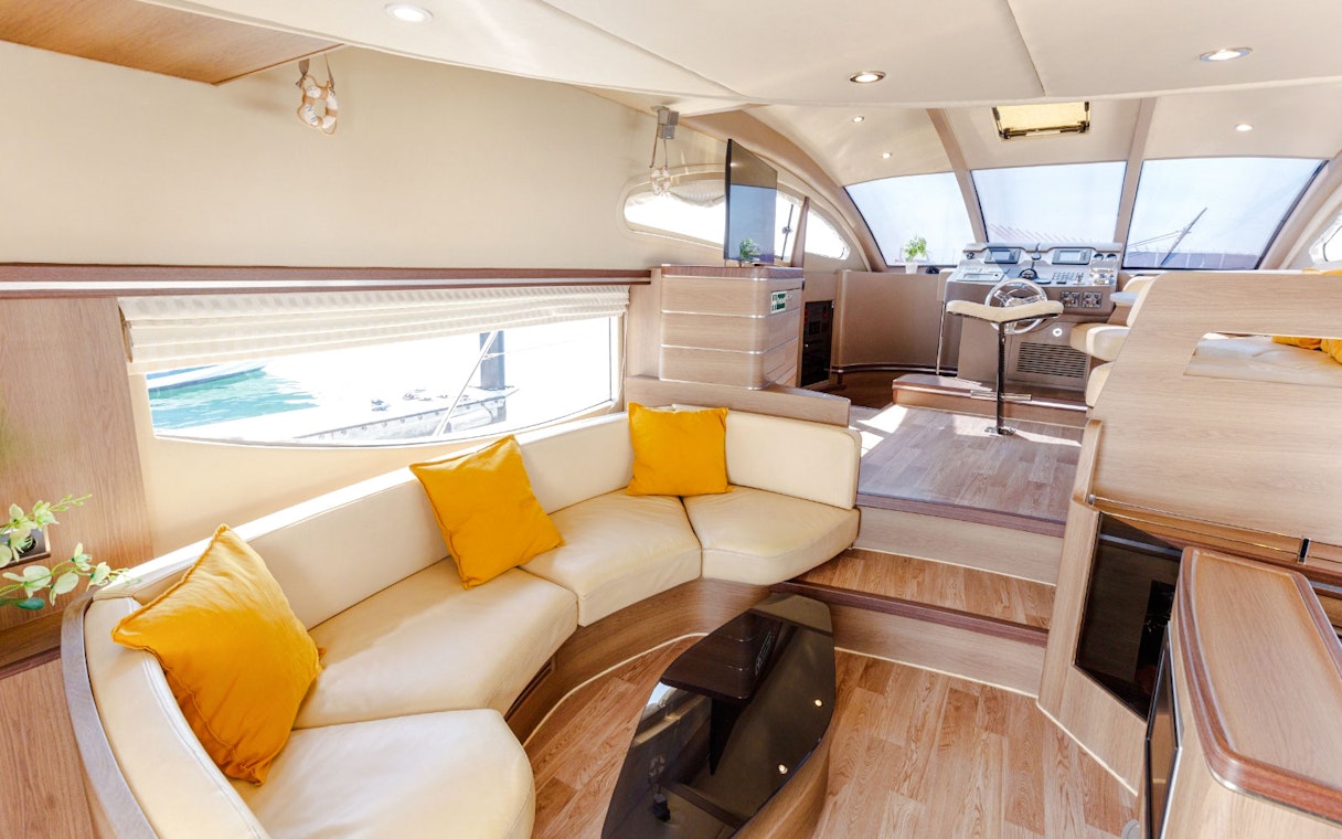 Interior seating area of VERONIKA Private Luxury Yacht with yellow cushions and helm view.
