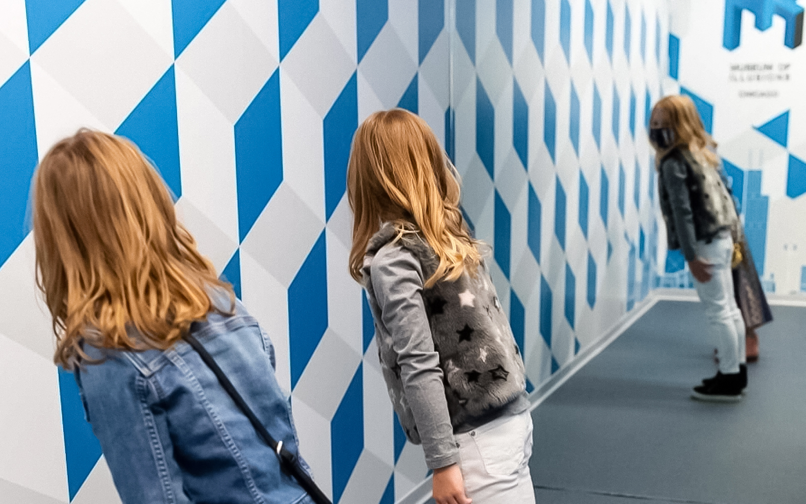 Visitors exploring a tilted room exhibit at the Museum of Illusions, Madrid.