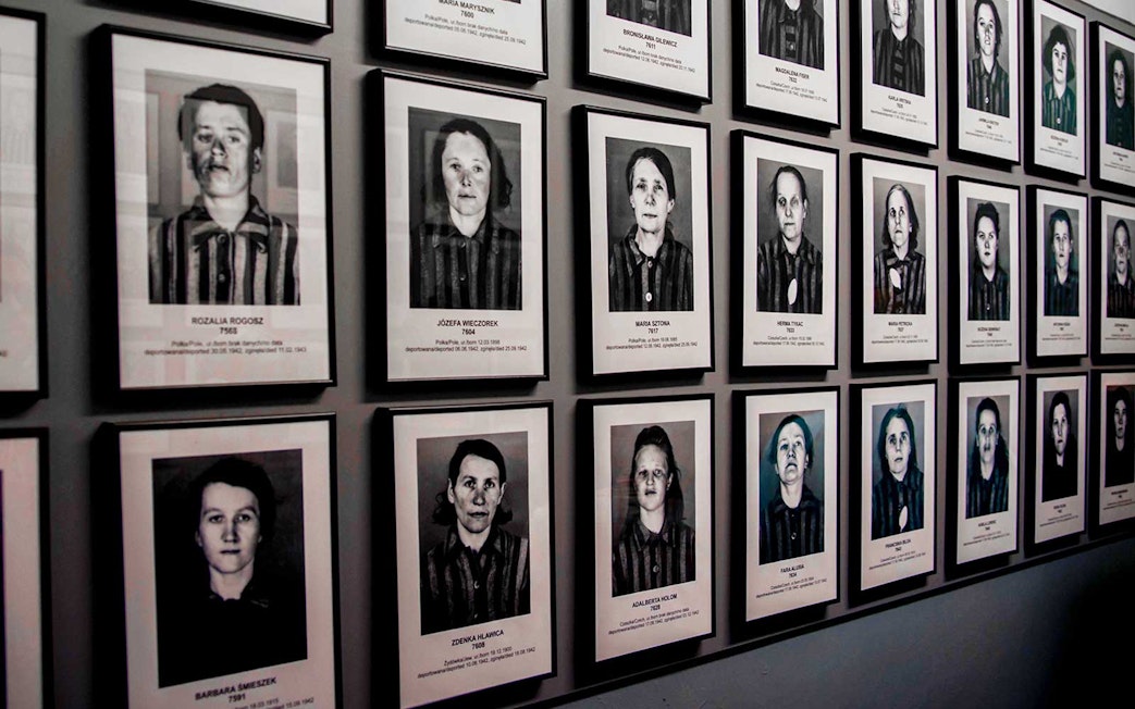 Portraits of Auschwitz-Birkenau prisoners displayed on a museum wall.