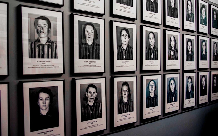 Portraits of Auschwitz-Birkenau prisoners displayed on a museum wall.