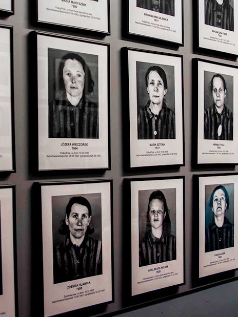 Portraits of Auschwitz-Birkenau prisoners displayed on a museum wall.