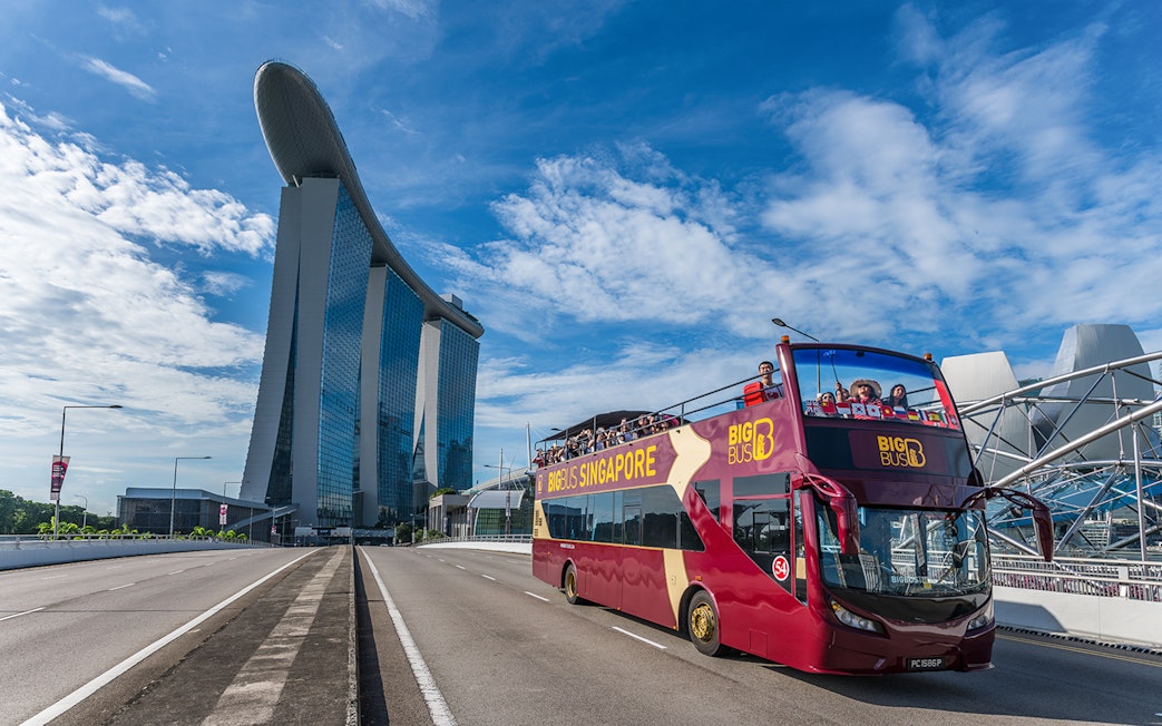 Tourists on a Singapore Hop-On-Hop-Off bus with Marina Bay Sands in the background.
