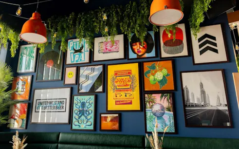 BrewDog wall art with vibrant posters and greenery, setting for craft beer tasting and meal experience.