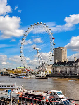 London Eye overlooking the River Thames with boats and cityscape in London, UK.