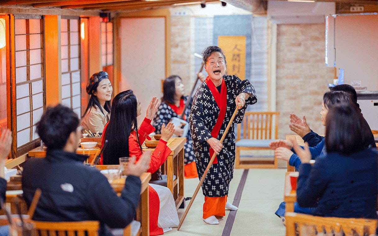 Cultural performance on Yakatabune Cruise with performer engaging guests in traditional attire.