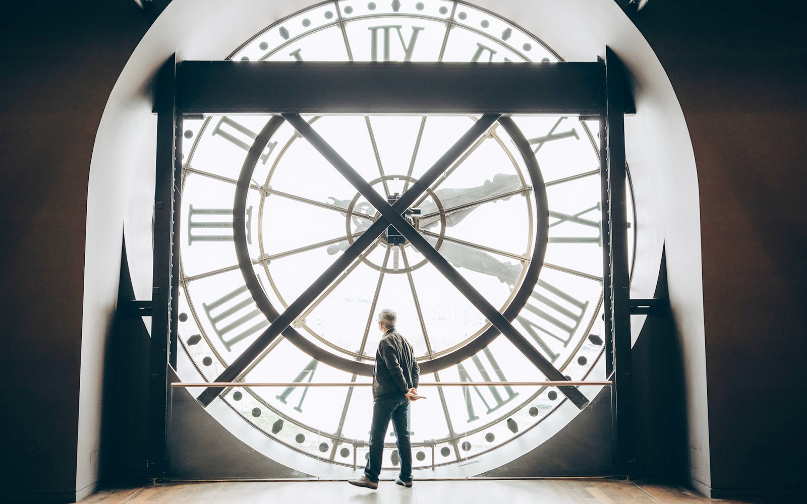 Tourist viewing through the large clock face inside Orsay Museum, Paris.