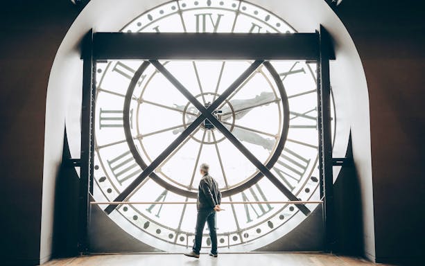 Tourist viewing through the large clock face inside Orsay Museum, Paris.
