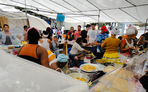 Vendors and visitors at Ipanema Hippie Fair, Rio de Janeiro, enjoying local food stalls.