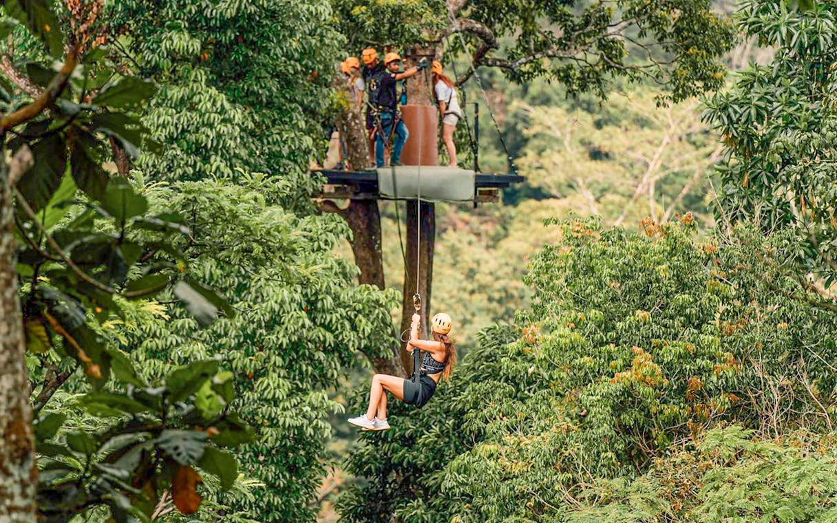 Person ziplining through lush forest in Phuket during ATV adventure tour.