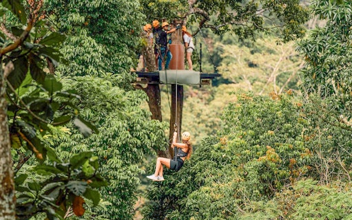 Person ziplining through lush forest in Phuket during ATV adventure tour.