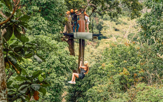 Person ziplining through lush forest in Phuket during ATV adventure tour.