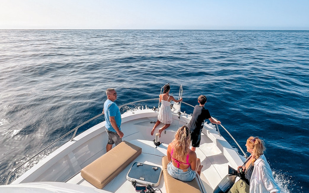 Tourists on a boat enjoying the ocean view during a dolphin and whale watching cruise in Gran Canaria.