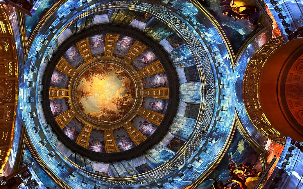 Dome interior with vibrant frescoes at Invalides Aura Immersive Experience, Paris.