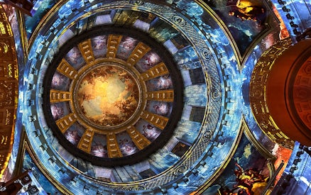 Dome interior with vibrant frescoes at Invalides Aura Immersive Experience, Paris.