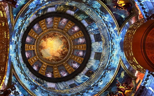 Dome interior with vibrant frescoes at Invalides Aura Immersive Experience, Paris.