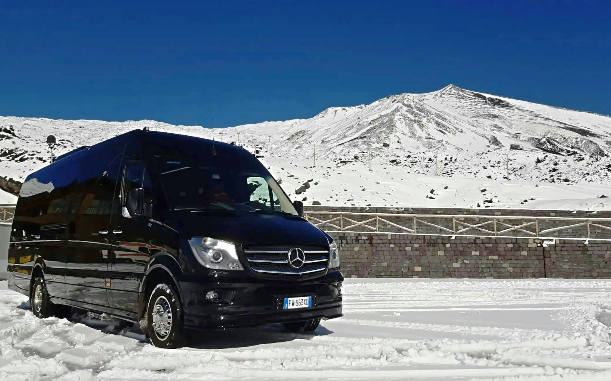 Tour van on snowy Mount Etna with clear blue sky in Sicily, Italy.