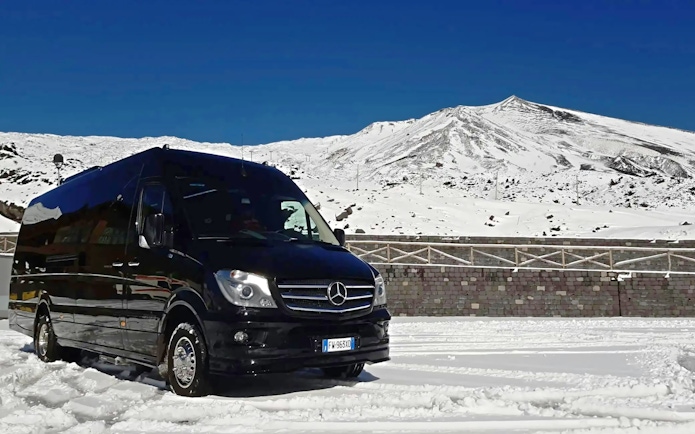 Tour van on snowy Mount Etna with clear blue sky in Sicily, Italy.
