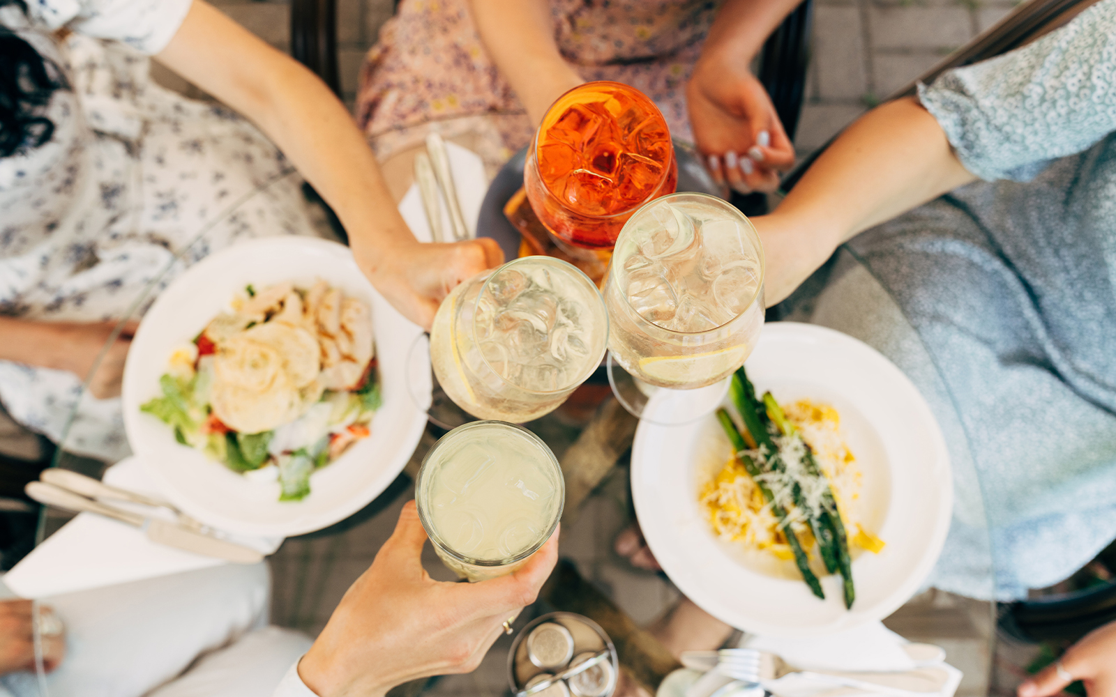 Tourists in Rome toasting with cocktails over plates of food.