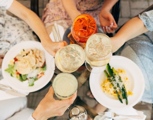 Tourists with cocktails over plates of food.