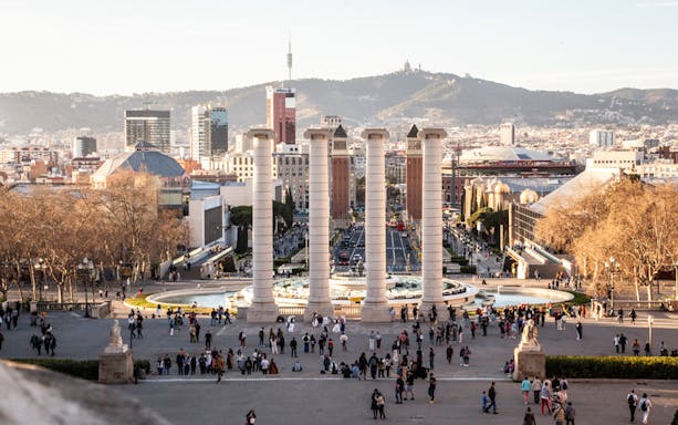 Montjuïc view with four columns and cityscape in Barcelona during guided walking tour.