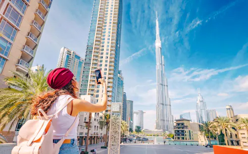 Tourist photographing Burj Khalifa during Dubai city tour.