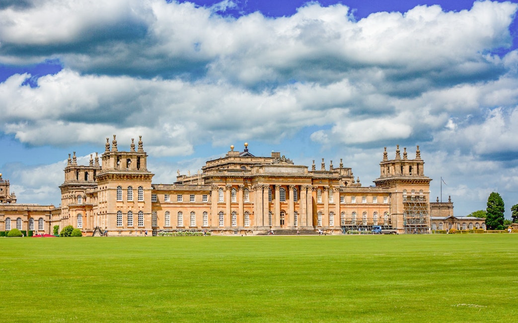 Blenheim Palace exterior with expansive lawn under a cloudy sky.