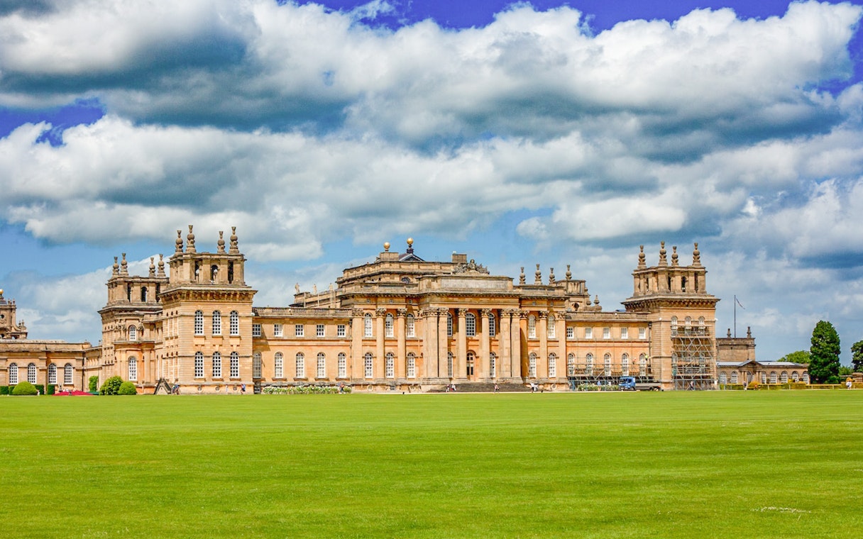 Blenheim Palace exterior with expansive lawn under a cloudy sky.