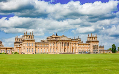 Blenheim Palace exterior with expansive lawn under a cloudy sky.