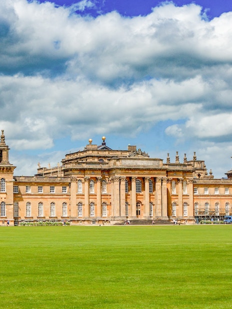 Blenheim Palace exterior with expansive lawn under a cloudy sky.