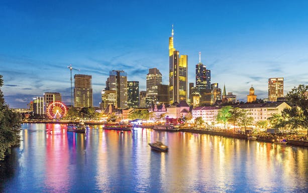 Frankfurt skyline at dusk with illuminated buildings and river during Evening Panorama Cruise.