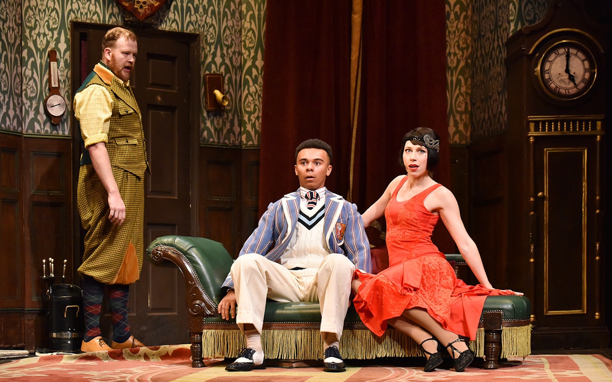 Actors in a comedic scene from "The Play That Goes Wrong" on stage.
