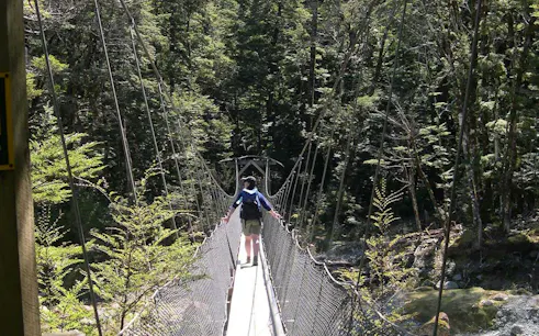 Hiker crossing a suspension bridge on the Routeburn Track, Queenstown.