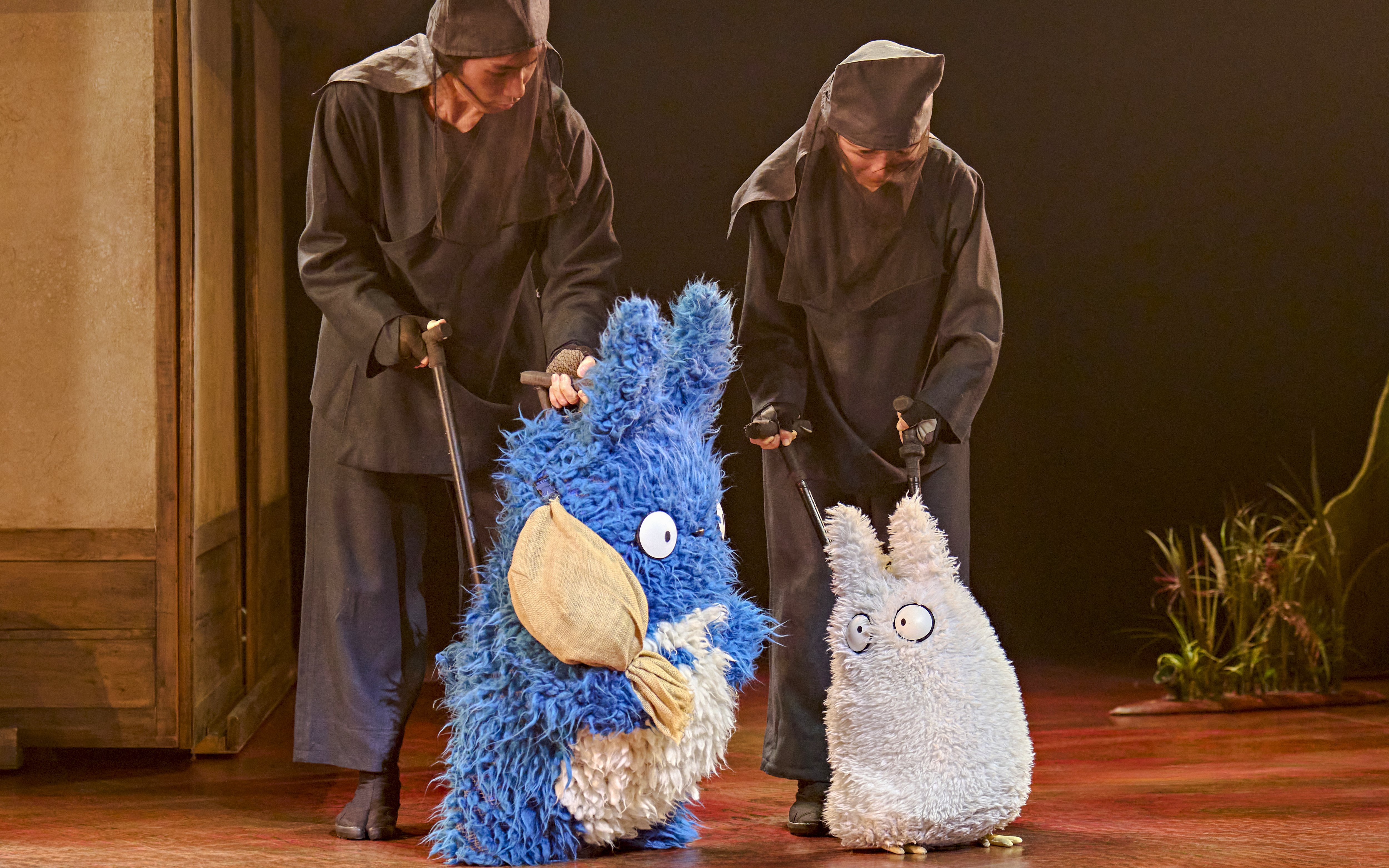 Performers with Totoro puppets in a stage production scene.