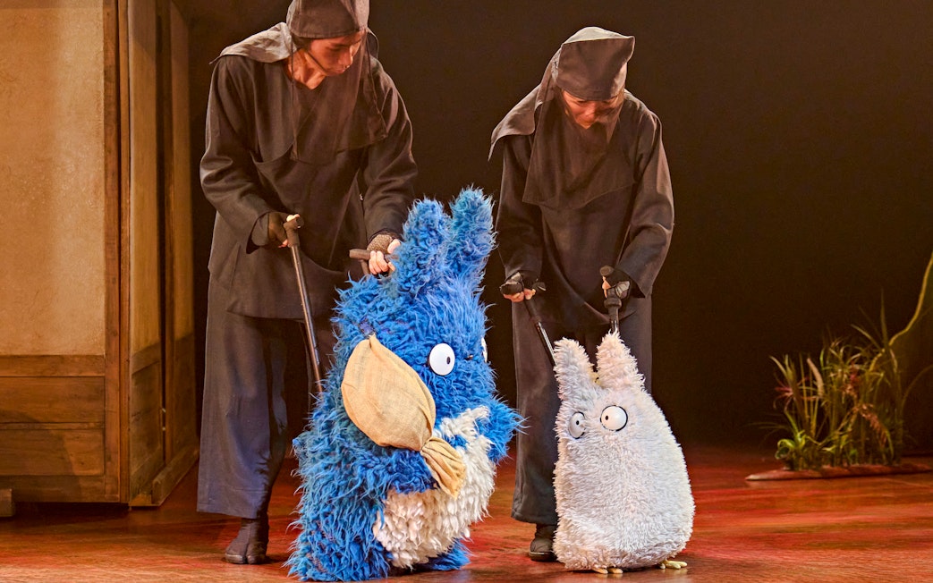 Performers with Totoro puppets in a stage production scene.