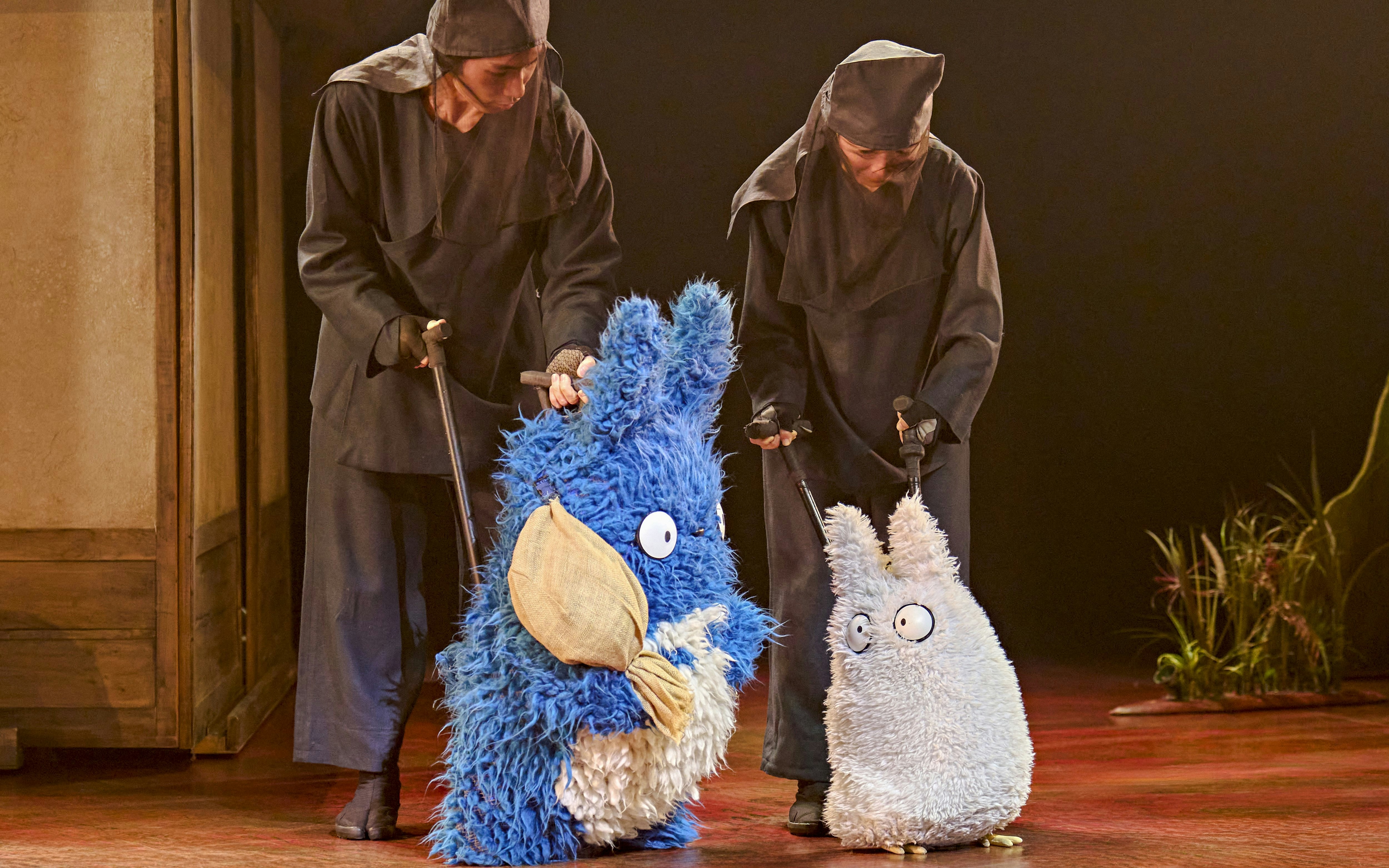 Performers with Totoro puppets in a stage production scene.