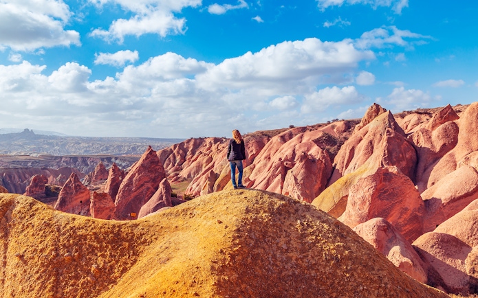 Girl overlooking Red Valley rock formations in Cappadocia, Turkey.