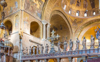 Interior of St. Mark's Basilica in Venice with ornate golden mosaics and statues.