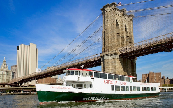 Cruise boat passing under Brooklyn Bridge on NYC landmarks tour.