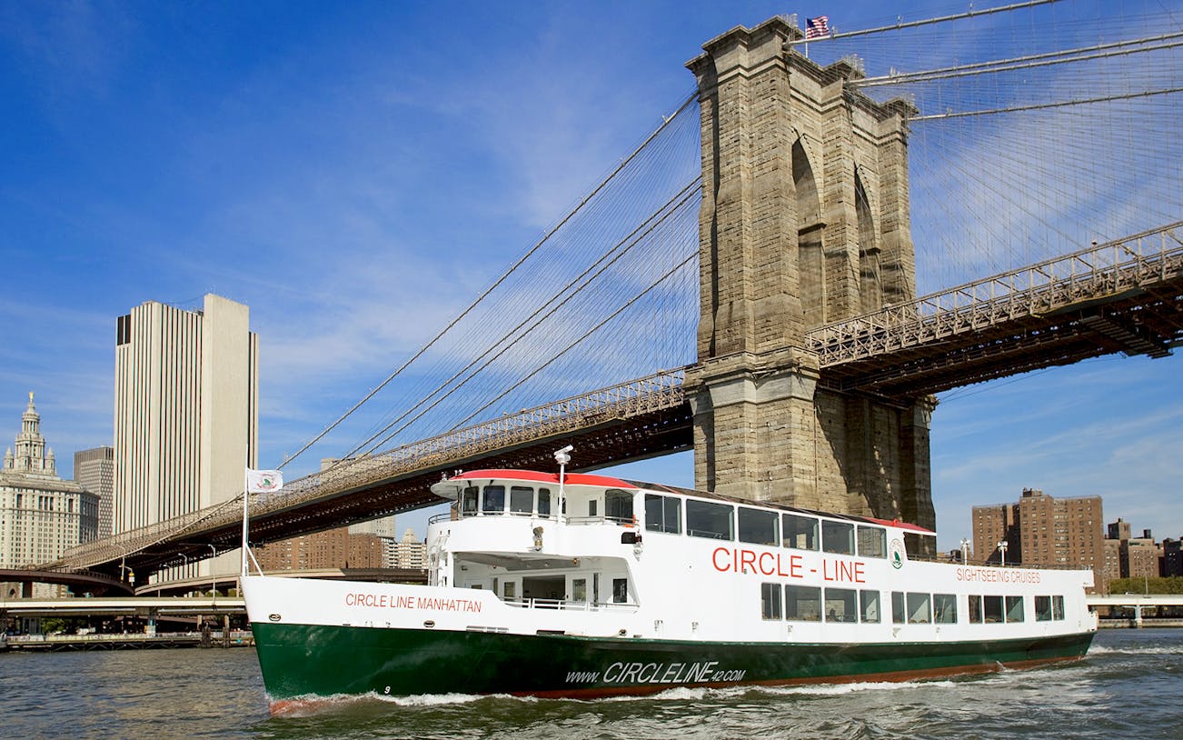 Cruise boat passing under Brooklyn Bridge on NYC landmarks tour.