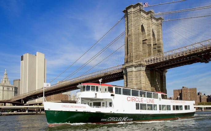 Cruise boat passing under Brooklyn Bridge on NYC landmarks tour.
