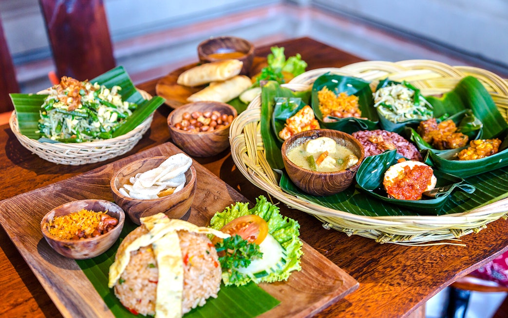 Balinese lunch spread with rice, vegetables, and traditional dishes on banana leaves.