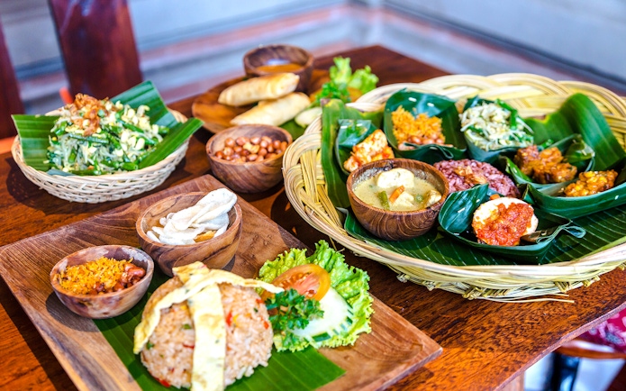 Balinese lunch spread with rice, vegetables, and traditional dishes on banana leaves.