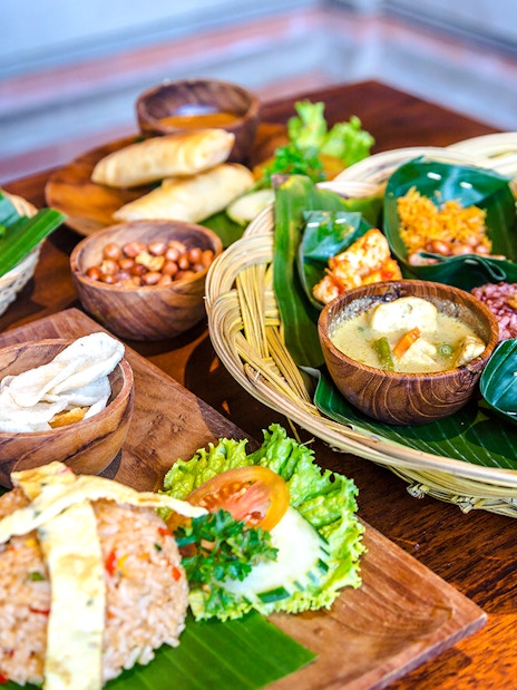 Balinese lunch spread with rice, vegetables, and traditional dishes on banana leaves.